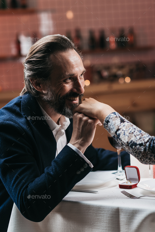 Handsome mature man proposing a beautiful woman to marry him in an elegant restaurant