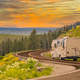 Camper Driving Down Road in The Beautiful Countryside Among Pine Trees and Flowers. - PhotoDune Item for Sale