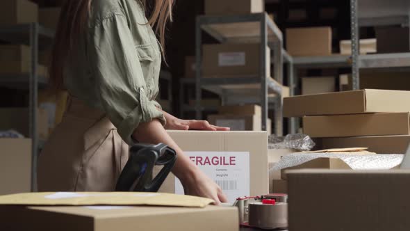 Female Post Mail Storage Worker Holding Tape Dispenser Sealing Shipping Box alt