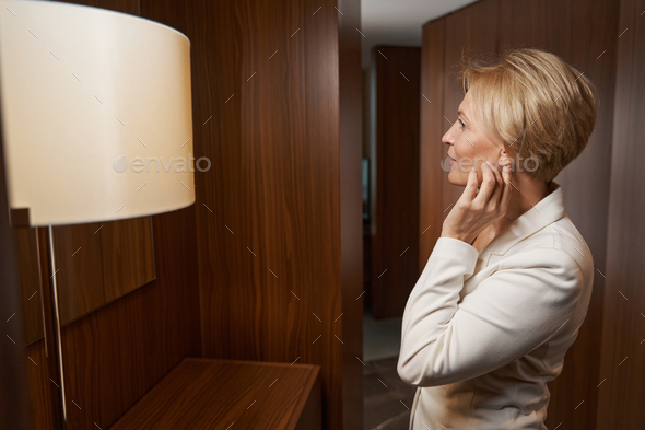 Elegant businesswoman looking in mirror in the hallway of hotel room