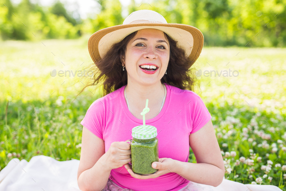 Young woman have fun in the park and drink green smoothies at a picnic  Stock Photo by Satura_