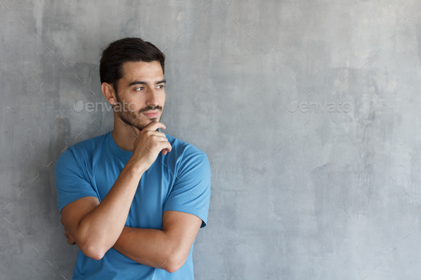 Young man holding chin as if thinking of something or analyzing situation, trying to solve problem