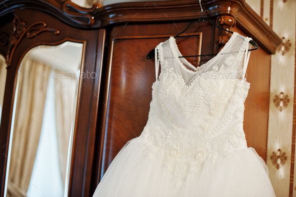 Wedding dress hanging on the rack on the wardrobe in the room.