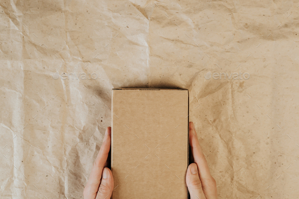Male hands holding cardboard box. Top view, layout. Delivery concept. Place for text, logo, ads