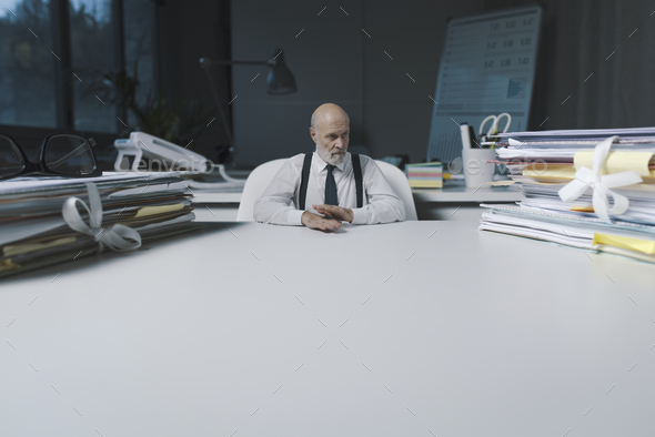 Small corporate businessman sitting at office desk