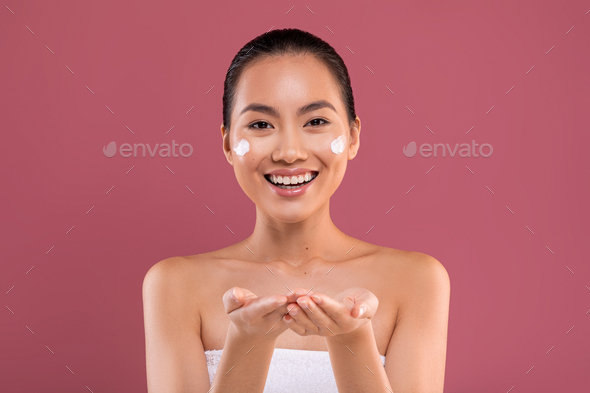 Cheerful asian woman holding something invisible on her hands - Stock Photo - Images