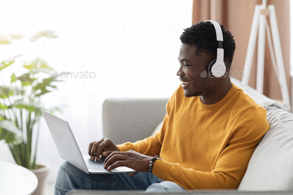 Handsome black guy having webinar, using laptop at home
