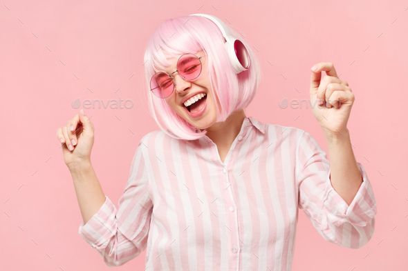 Young laughing woman wearing glasses and wireless headphones, dancing to  favorite music Stock Photo by damirkhabirov