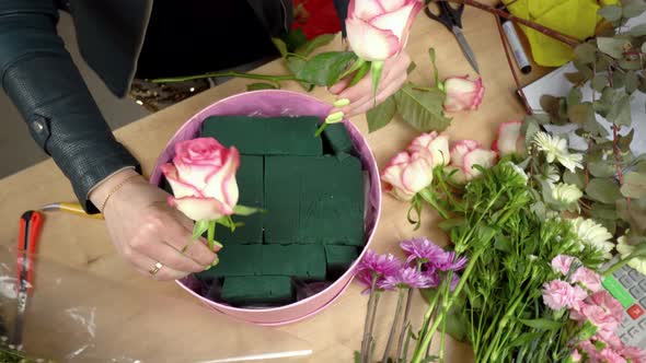 Close-up of the hands of a female florist packing a beautiful composition alt