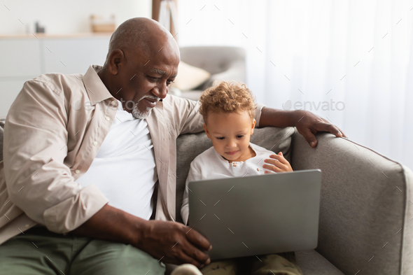 African American Grandpa And Grandson Using Laptop Computer At Home