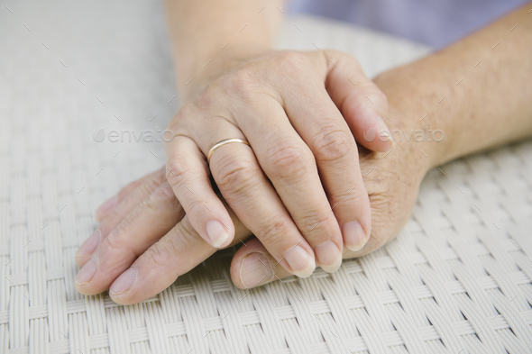 Senior couple sitting at garden table holding hands, close-up - Stock Photo - Images