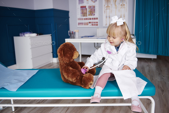 Girl with stethoscope examining teddy in medical practice