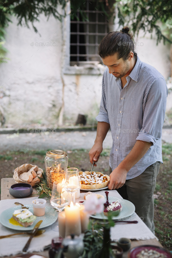 Man arranging a romantic candlelight meal outdoors