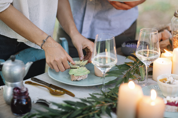 Close-up of couple preparing a romantic candlelight meal outdoors