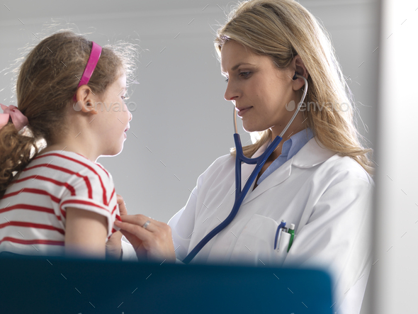 Female doctor listening to a young girl heart using a stethoscope in a clinic