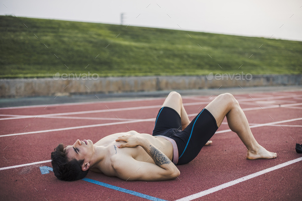 Athlete lying resting on a tartan track after finishing a race