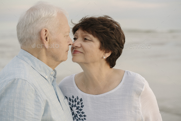Senior couple rubbing noses in front of the sea, Liepaja, Latvia