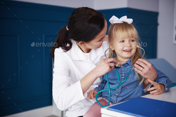 Doctor and girl playing with stethoscope in medical practice