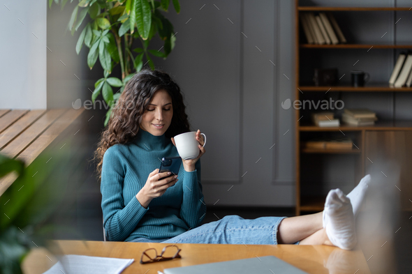 Happy young office worker woman sitting relaxed with feet on table