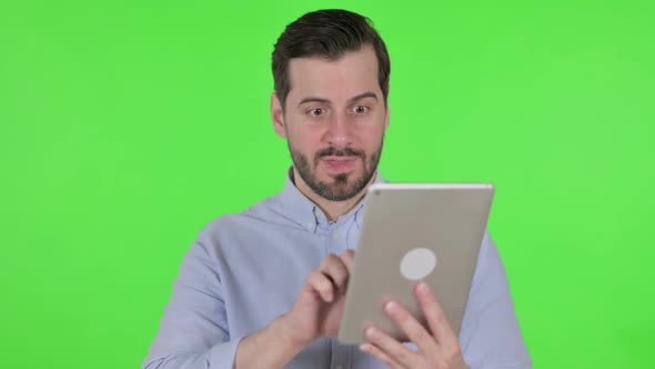 Portrait of Man Celebrating on Tablet in Office Green Screen alt