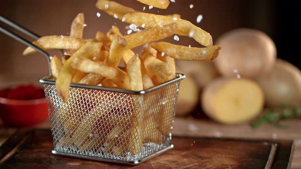 Super Slow Motion Shot of Falling Fresh French Fries on Wooden Table and Adding Salt at 1000Fps alt