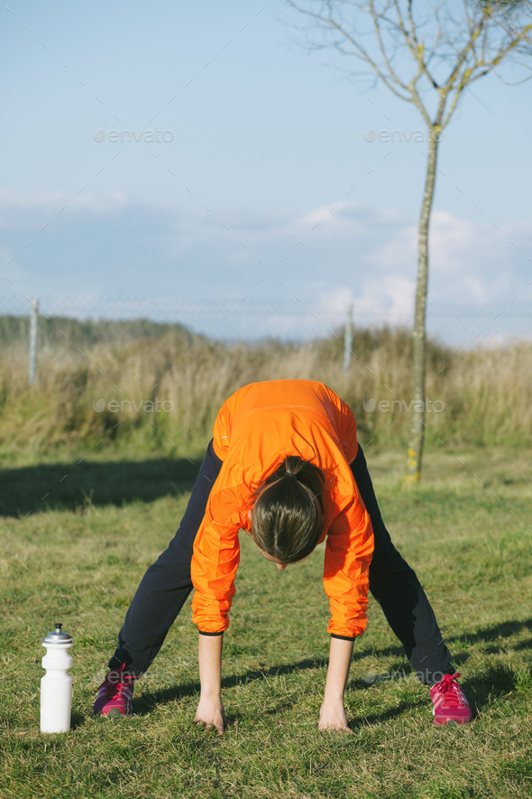 Young female jogger stretching on a meadow - Stock Photo - Images