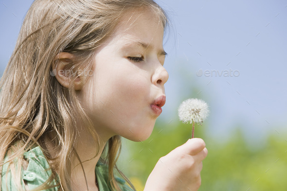 Germany, Bavaria, Munich, Girl (6-7) blowing dandelion seeds, eyes closed, side view, portrait