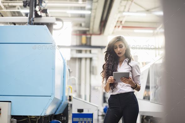 Woman using tablet at machine in factory shop floor - Stock Photo - Images