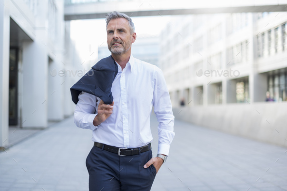 Portrait of businessman walking at courtyard of modern office building - Stock Photo - Images