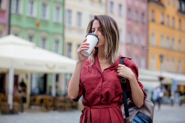 young woman drinks coffee on the go walking down the street