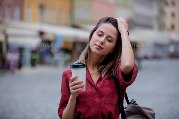 young woman drinks coffee on the go walking down the street