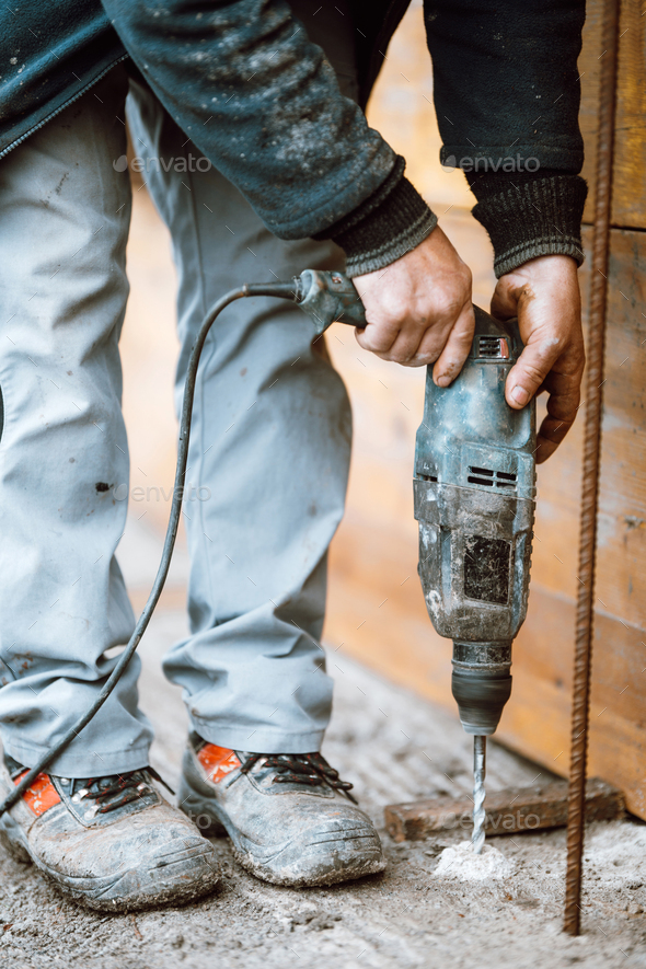 Builder working with rotary hammer drill