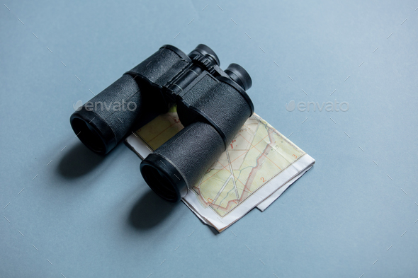 Binocular and vintage map on gray background. Side view