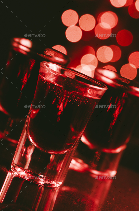 Red alcohol cocktails in shot glasses over red bokeh - Stock Photo - Images
