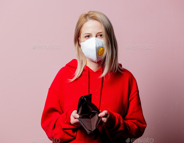 Woman in FFP2 anti-dust standart face mask hold empty wallet on pink background