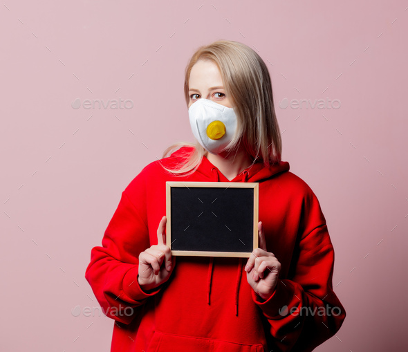 Woman in FFP2 anti-dust standart face mask hold blackboard on pink background
