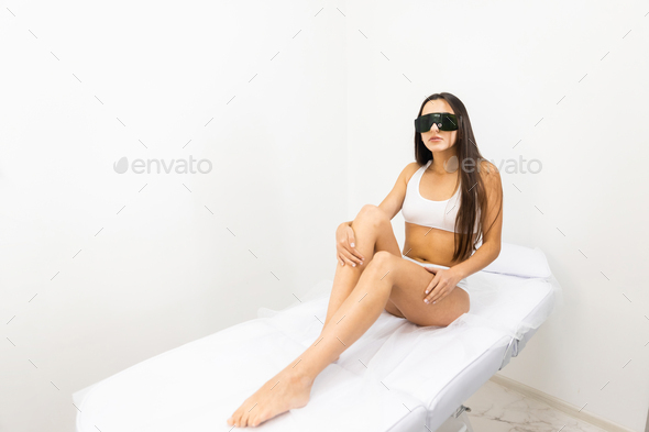 Young girl in white underwear and safety glasses on a couch in a laser hair removal salon