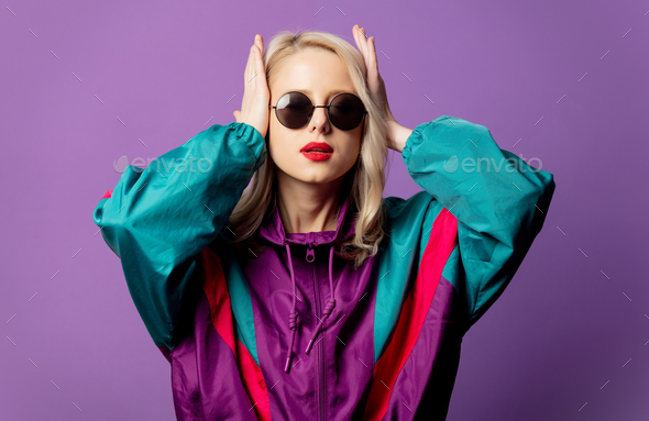 Style blonde in 80s windbreaker and roud sunglasses on purple