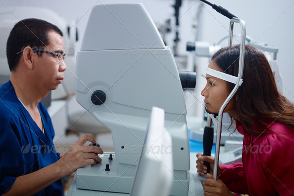Eyesight exam in clinic with Asian doctor and female patient - Stock Photo - Images