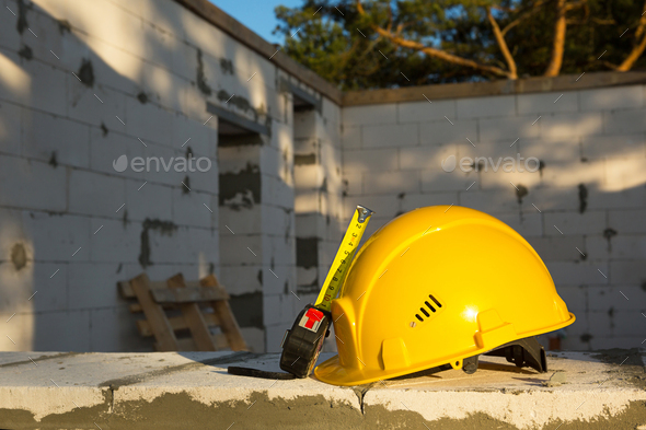Construction hardhat and measuring tape measure on the window of a house