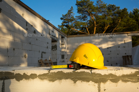 Construction hardhat and measuring tape measure on the window of a house