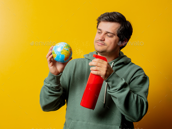 Man with Earth globe and disinfection spray on yellow background
