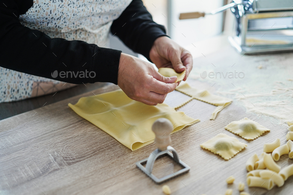 Woman prepare fresh ravioli inside pasta factory - Focus on left hand