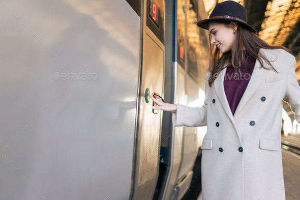 Cheerful woman presses button on the train door to enter. Female tourist missed the train.