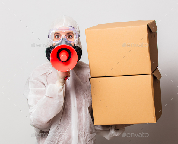 postman in protection suit and glasses with mask holds delivery boxes