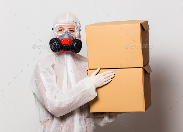 postman in protection suit and glasses with mask holds delivery boxes