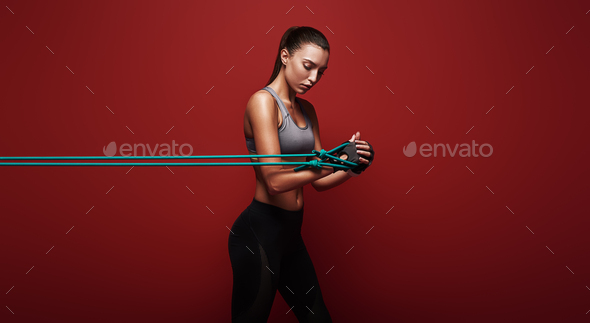 Never let good enough be enough Sportswoman performs exercises with resistance band over red