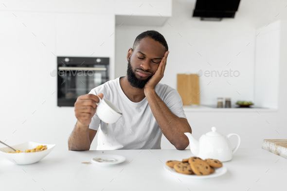 Black man yawning, pouring coffee away from cup Stock Photo by Prostock ...