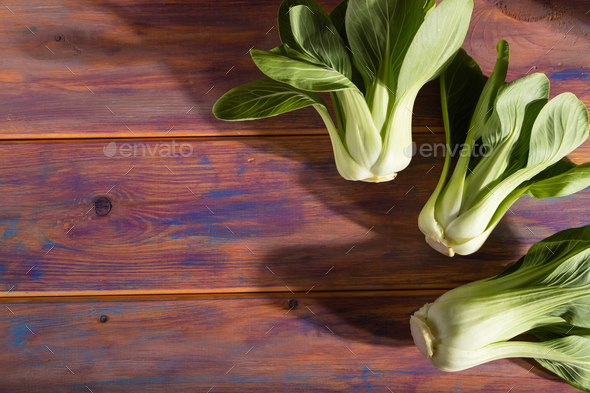 Fresh green bok choy or pac choi chinese cabbage on a colored wooden background. Hard light