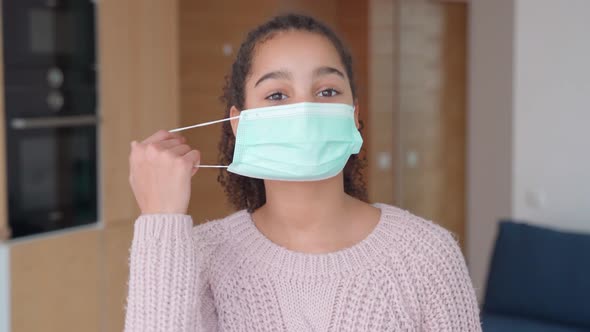 Happy African American Young Teen Girl Takes Off Protective Mask Indoors